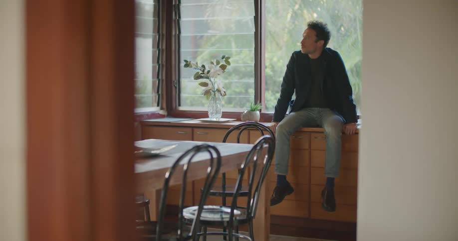 Man sits on furniture near window flipping through book