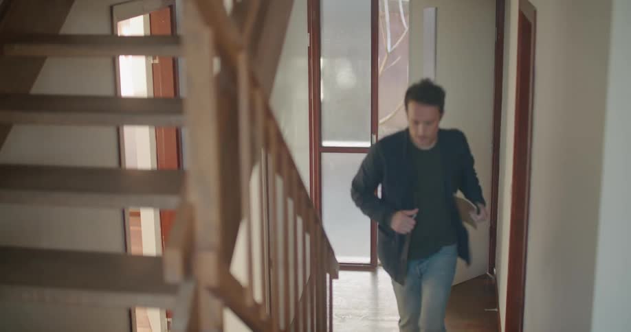 A man opens a door enters and jogs up the stairs carrying a notebook and pen