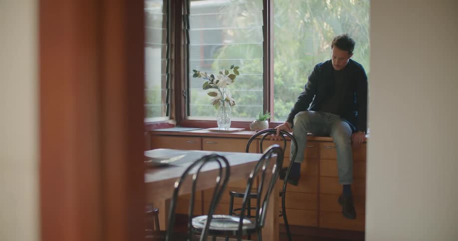 A man sitting on a counter and chair in a kitchen