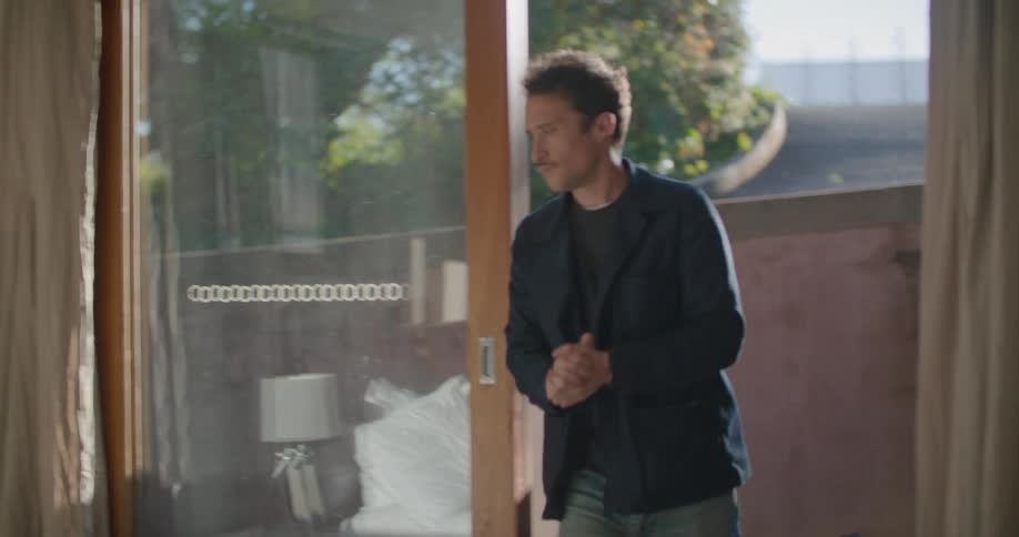 A man standing outside on his patio is deep in though before returning to his laptop