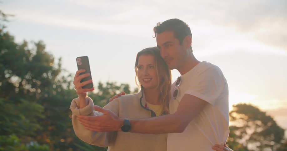 Two people are outdoors and taking a selfie at dusk