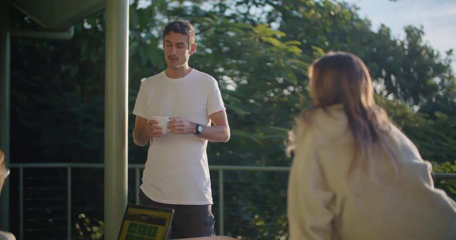A man chats with a woman while drinking coffee outdoors during the day