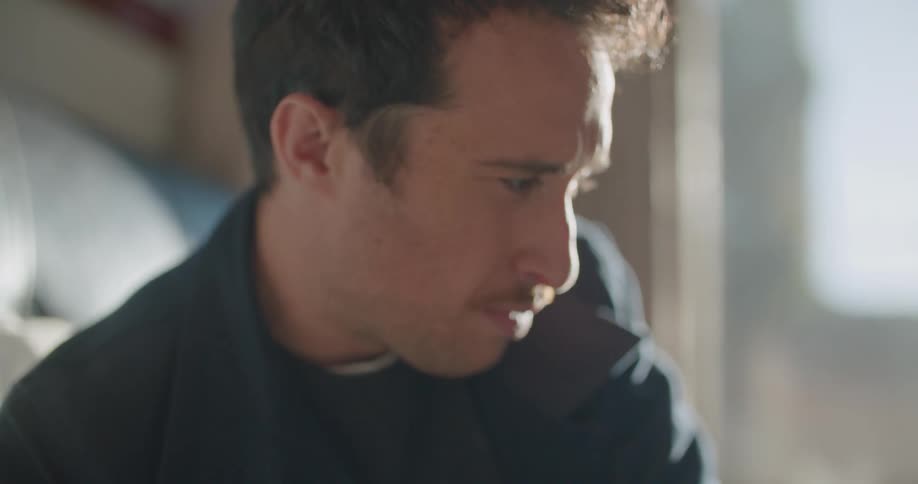 A man concentrates on his drawing and briefly looks up at his reference