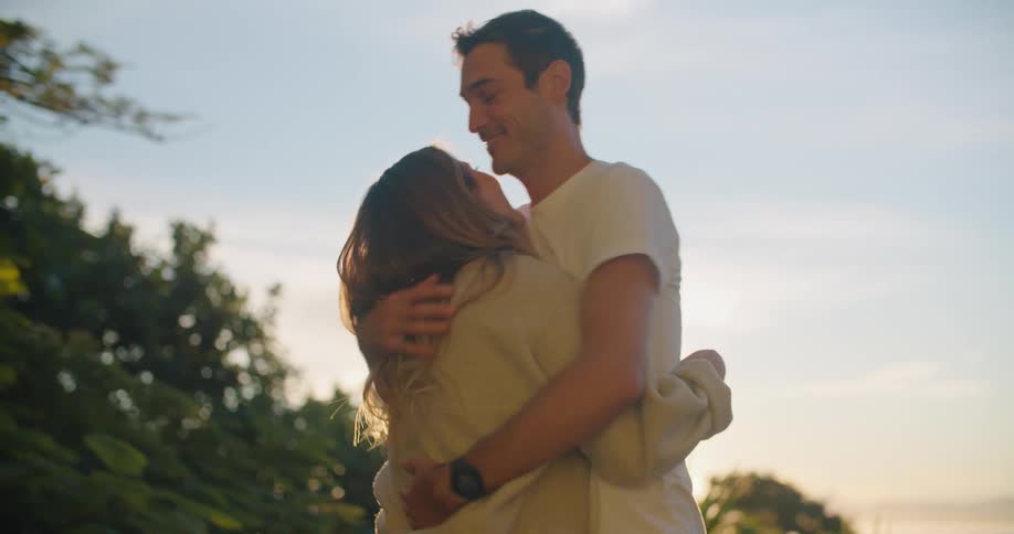 Man and woman hug smiling before walking away hand in hand on sunny day
