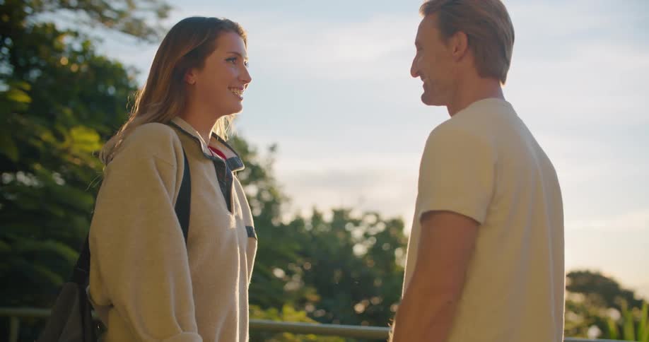 Woman approaches a man and they hug and smile on a sunny day