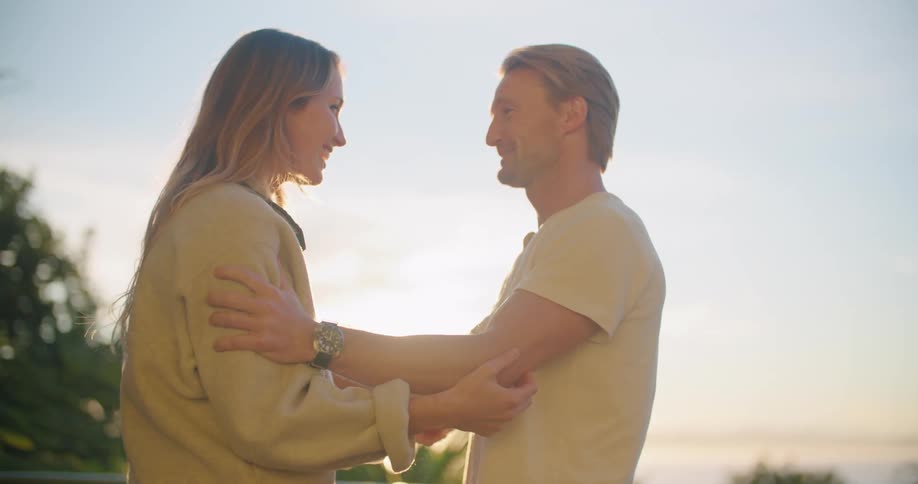 A man and woman greet each other with a hug outdoors during the day