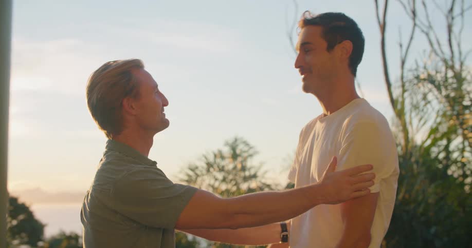 Two men hug as they meet up on a walkway