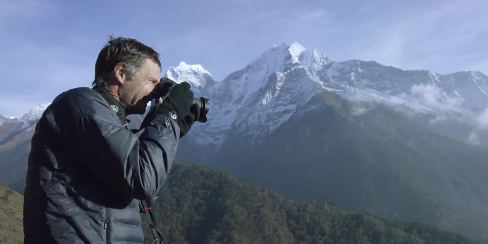 A man takes pictures of mountains outside in the winter