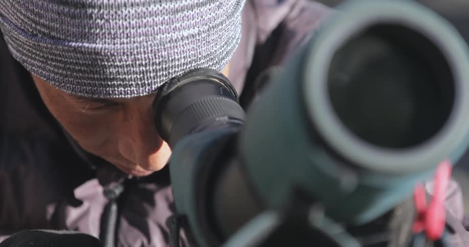 A man in a hat looks through a telescope