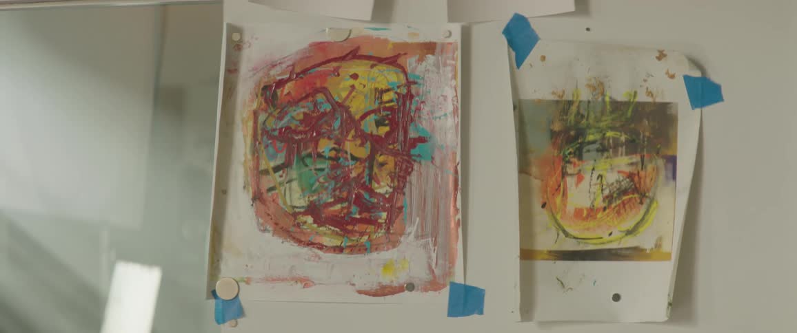 Watercolor abstract paintings over paper taped on a wall