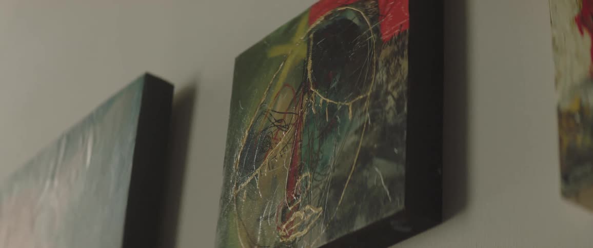 Three paintings are hanging up on a wall