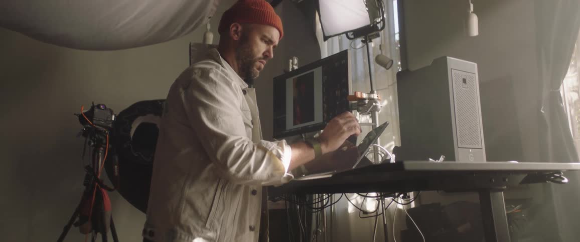 Painter drawing on a tablet next to a computer in a studio