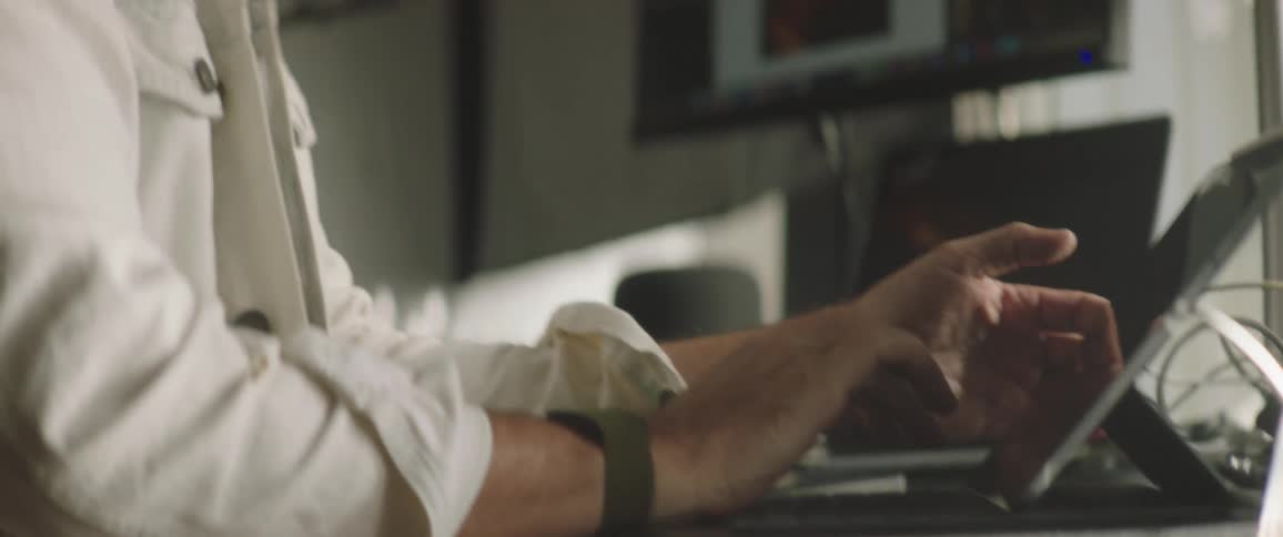 A man with a hat in a room using a tablet with a computer screen and a microphone in the background