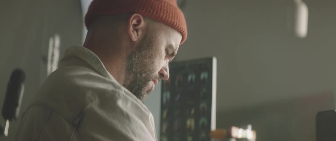 A man uses a tablet at a standing desk with a larger monitor nearby