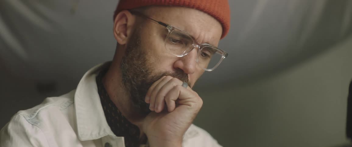 A man with a hat and glasses in a studio looking at a tablet