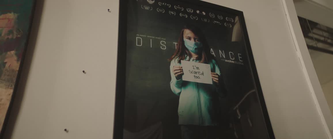 Poster hanging on wall shows woman with health message related to distancing
