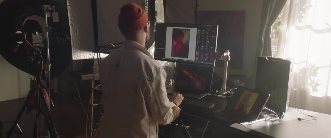 A photographer reviews photographs on a computer in a photography studio