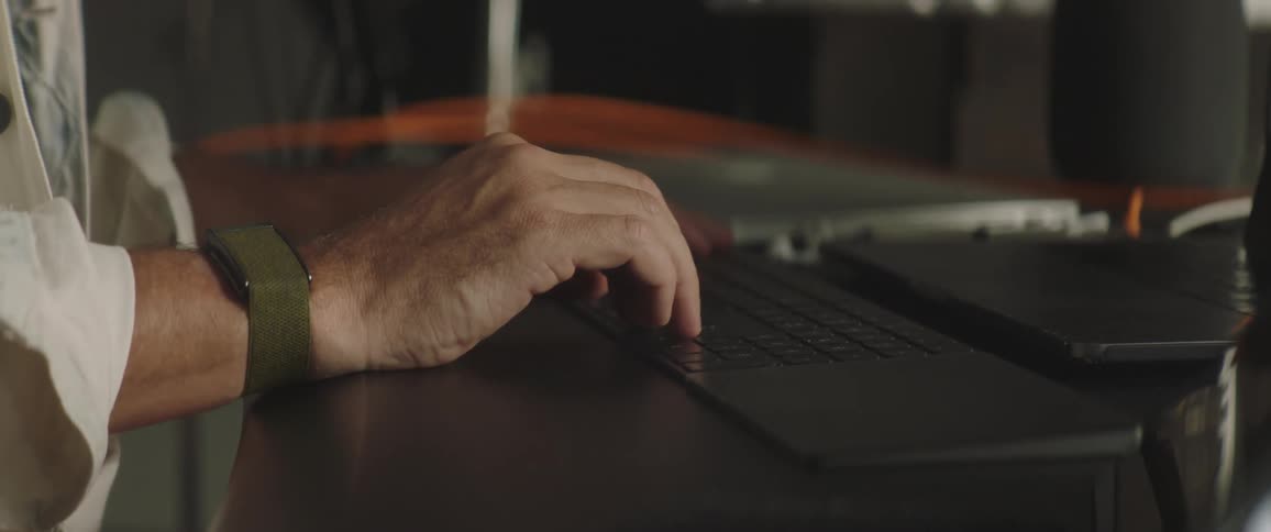 A person typin gon a keyboard over a desk in an office