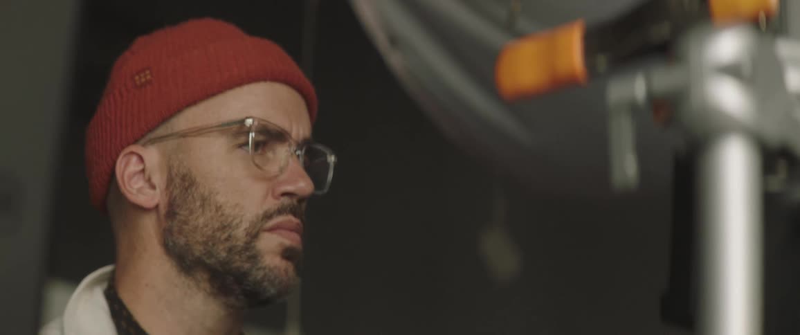 A man is standing in a room and wearing a hat and glasses