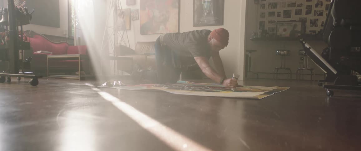 A man is sitting on the ground and painting on a canvas
