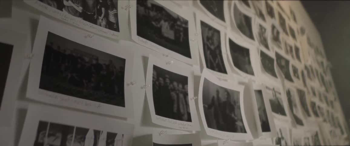 A room with a wall of photos with thumbtacks