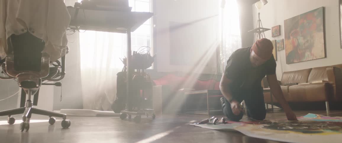 A man is painting on the floor on a large canvas