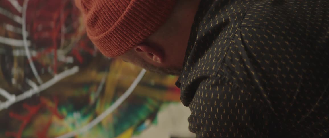 A person squeezes a tube of paint across a large canvas
