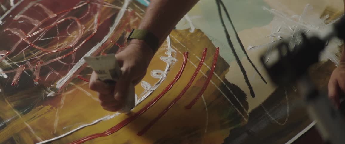 A person is painting on a canvas on the ground