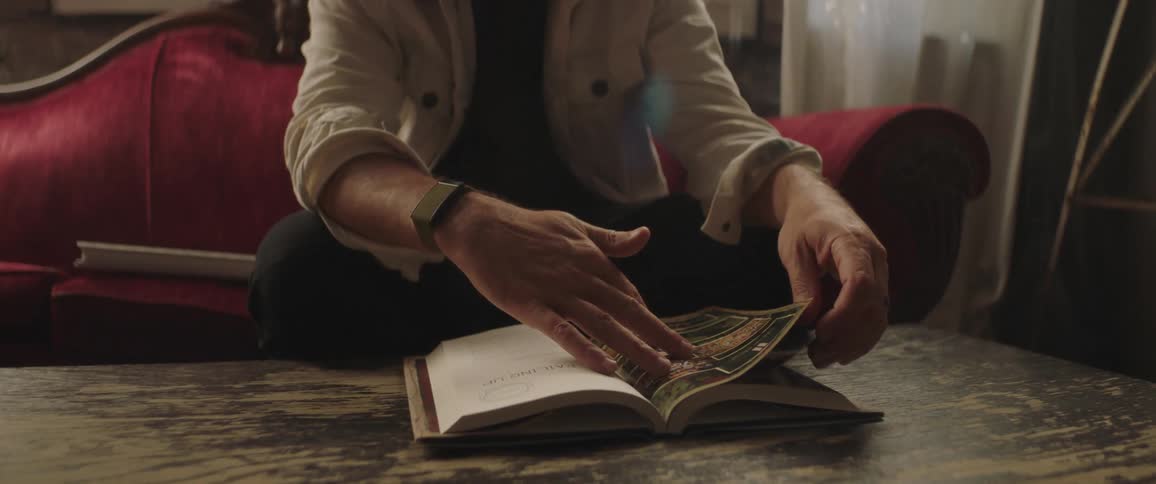 A man is flipping through a book on the coffee table