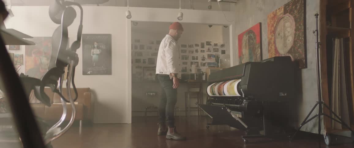 Artist working on a studio printing artwork on a large printer