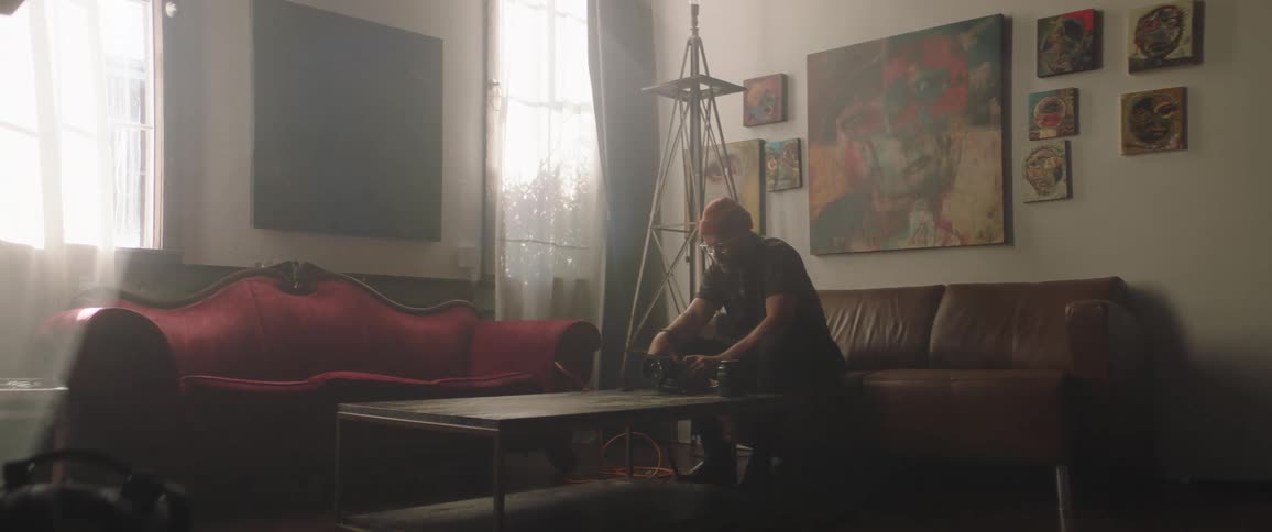 A man is working on a device on the couch