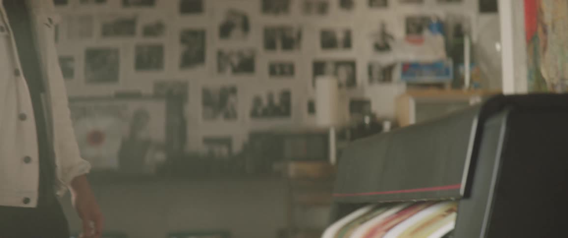 A man is standing in a room and a machine is printing pictures