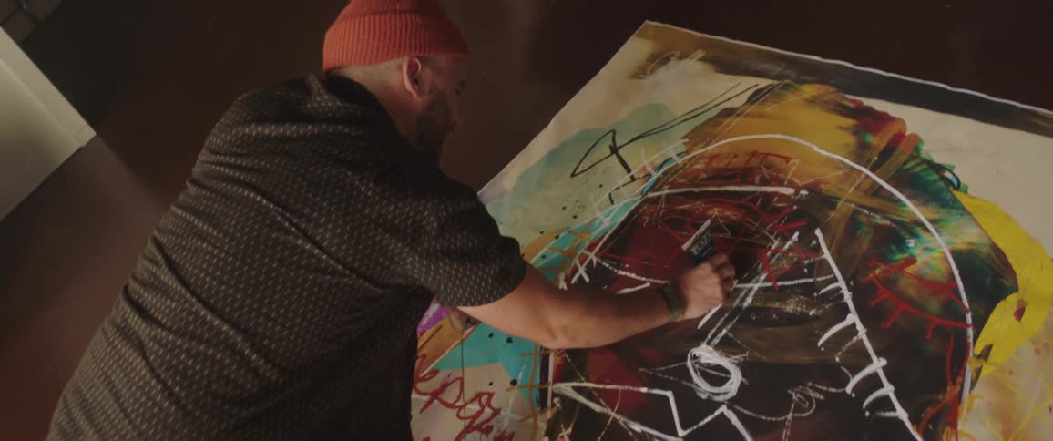 Artist wearing red knit cap adds adds paint to canvas