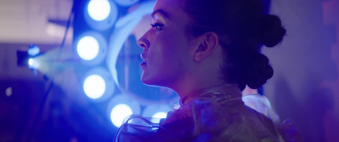 A female model poses in front of a ring of lights with a small spotlight projecting nearby