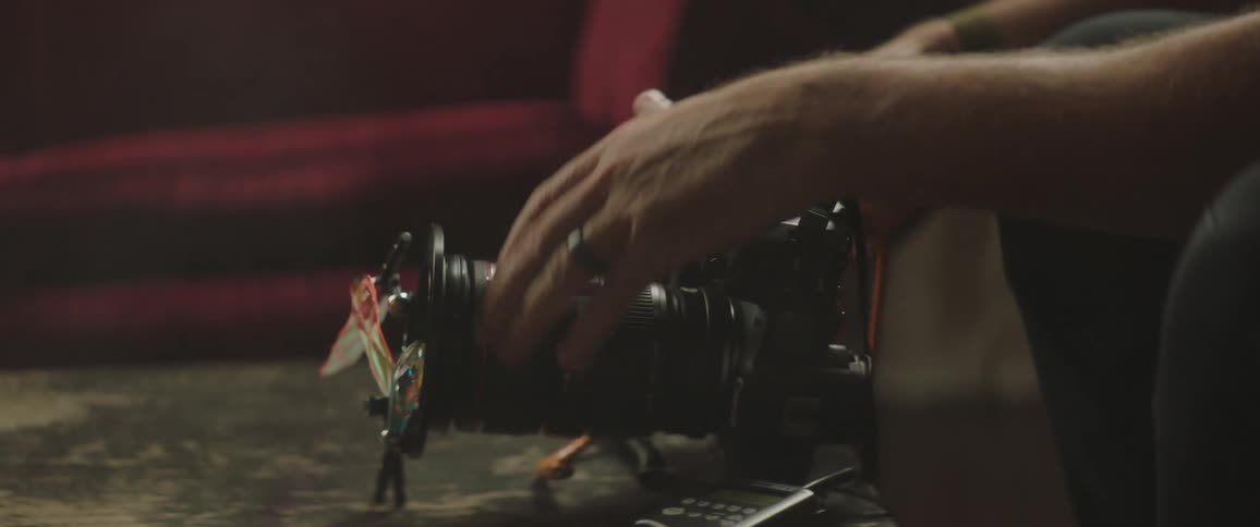 Photographer wearing red knit hat sits working on camera