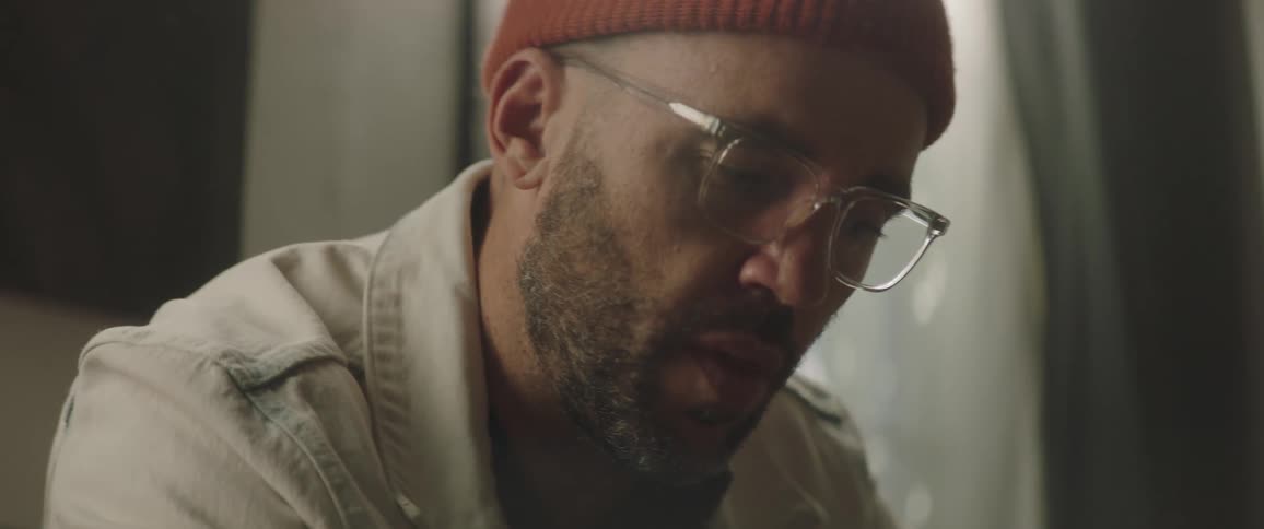 A man is sitting in a room and wearing glasses