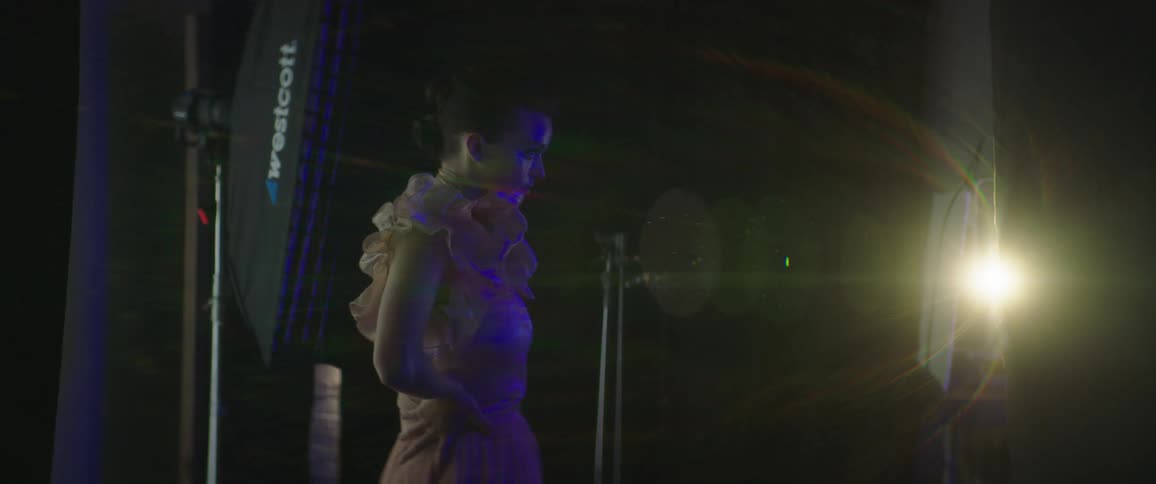 Female fashion model poses in dark as colored light shines across her