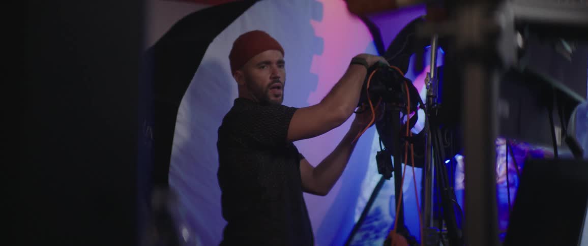 A photographer stands in front of a large white flash screen during a photo shoot