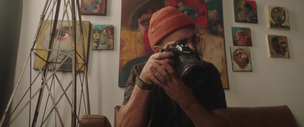 A man looks through a professional camera sitting in his home