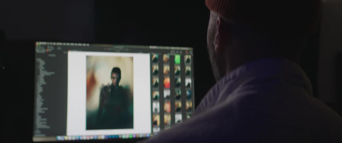 Photographer editing photos on a computer inside a dimly lit studio