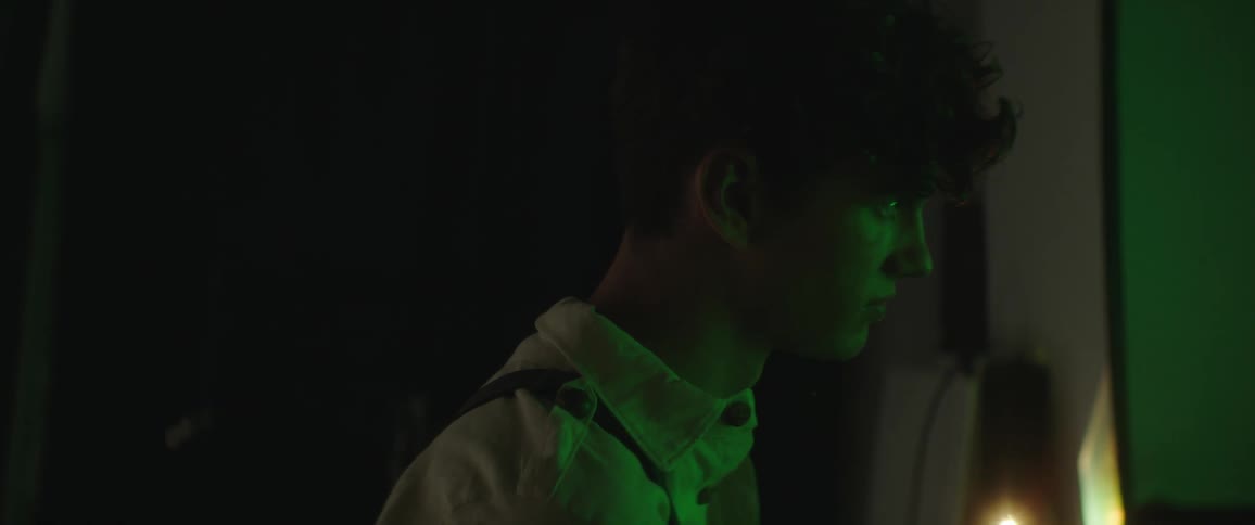 A man is standing in a room at night and camera is flashing