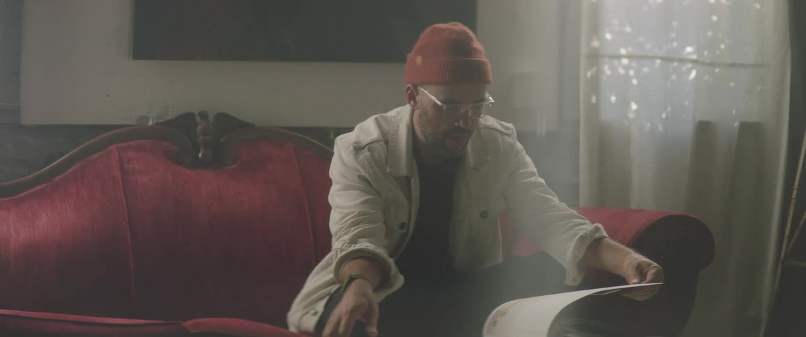 A man sits on the couch flipping through a book
