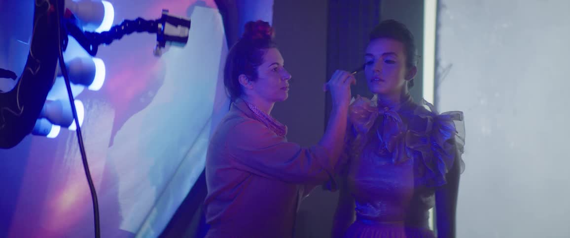 A woman getting her makeup done by someone else at a photo shoot