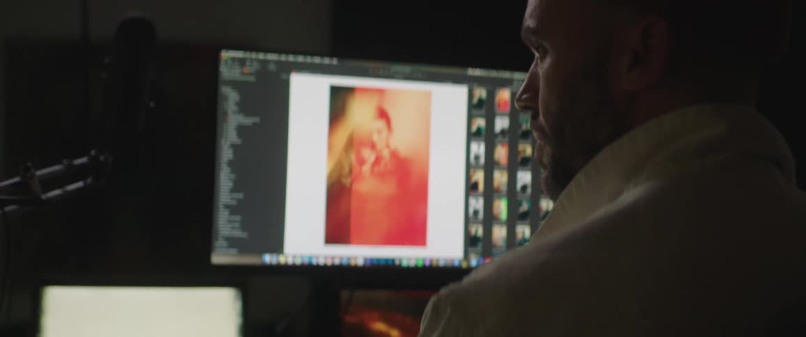 Photographer editing pictures on a computer inside a dimly lit studio