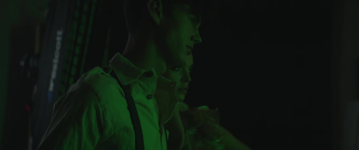 A man and a woman in a room with flashing lights and a wall in the background