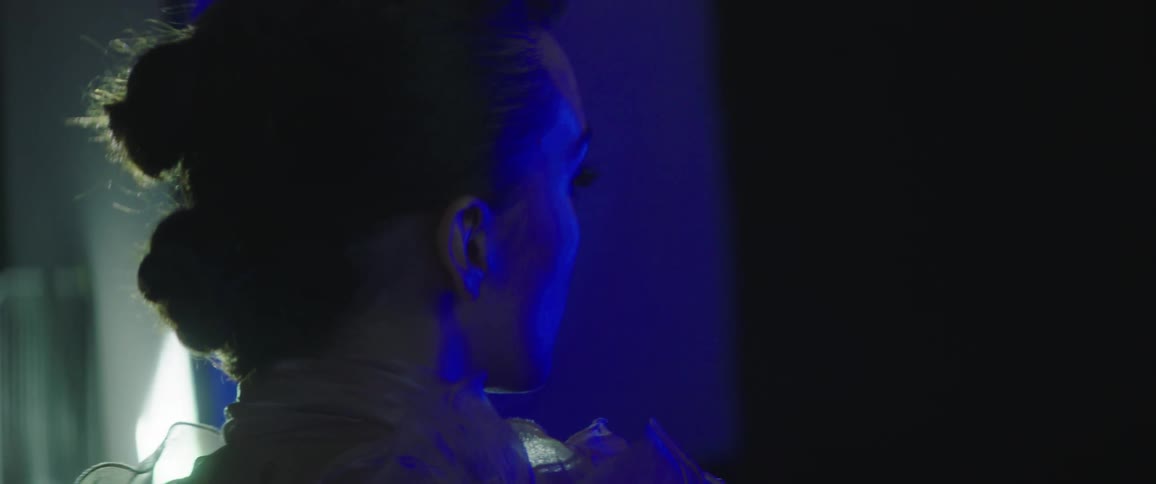 A woman posing at a photo shoot inside of a room with blue lighting