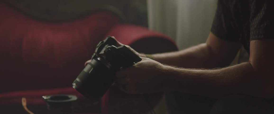 A man sitting in a living room holding his camera
