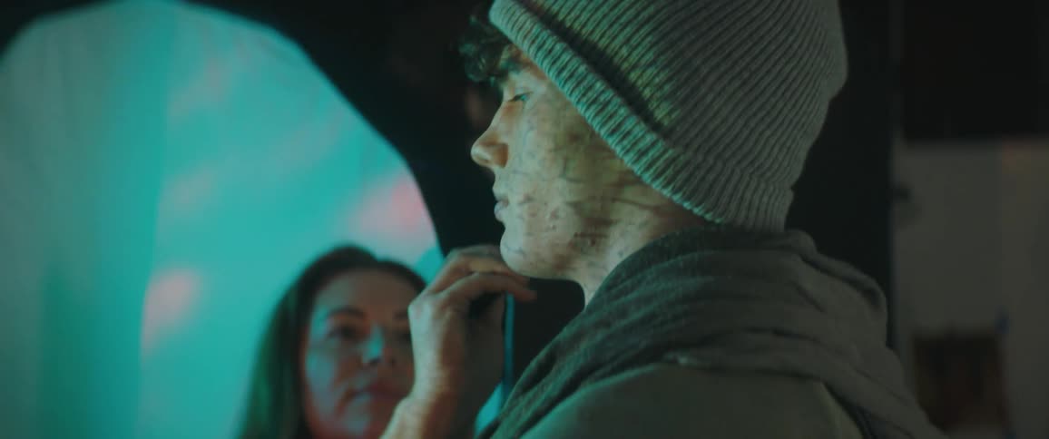 Female makeup artist touches up makeup on male model as lighting change colors