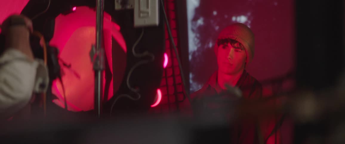 A man in a studio with a camera taking a picture of another man with a hat and with a screen in the background
