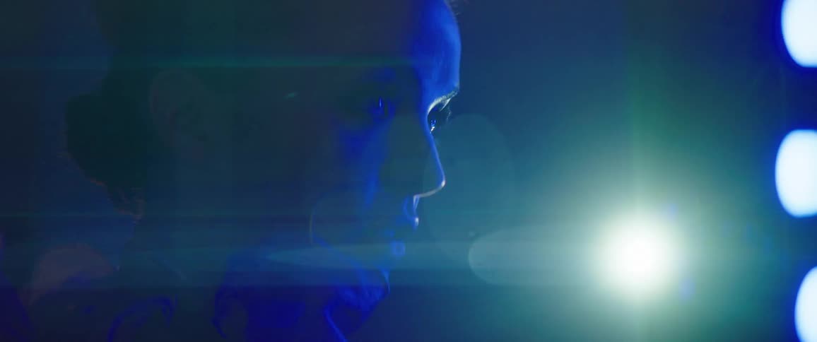 A female model poses as she is illuminated by a blue light in a dark room